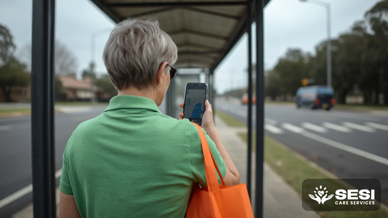 An older woman seen from behind at a suburban bus stop checking a map on her phone, an orange shopping bag over her arm