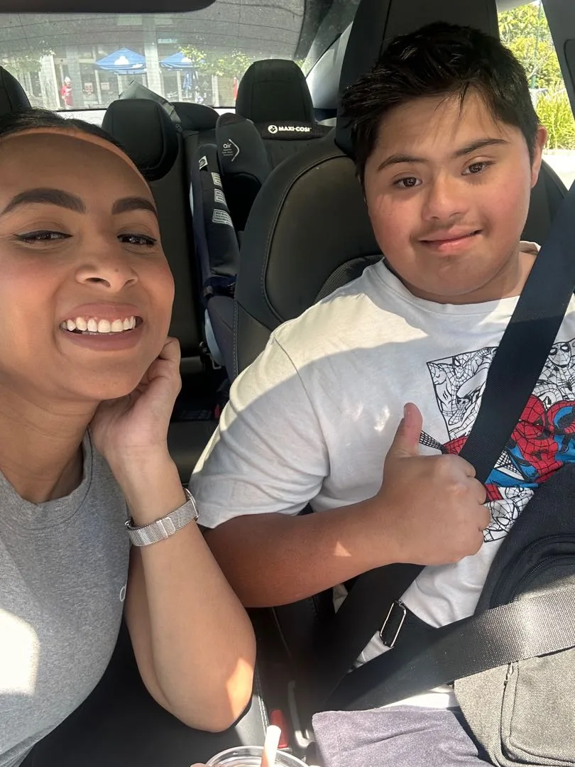 A SESI support worker and a young person smiling together in the car, heading out for the afternoon.
