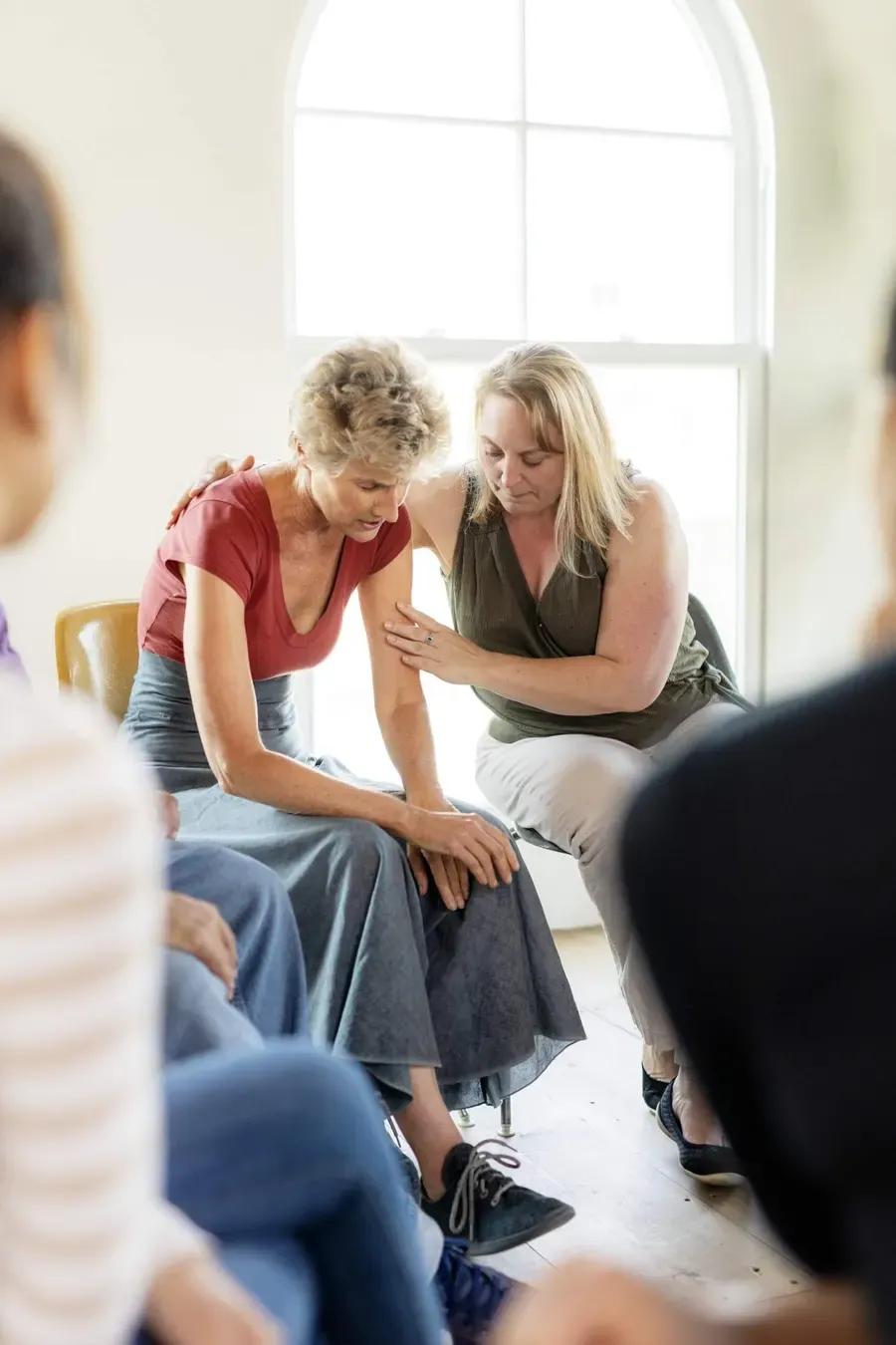 A recovery coach comforting a woman with a reassuring hand on her shoulder
