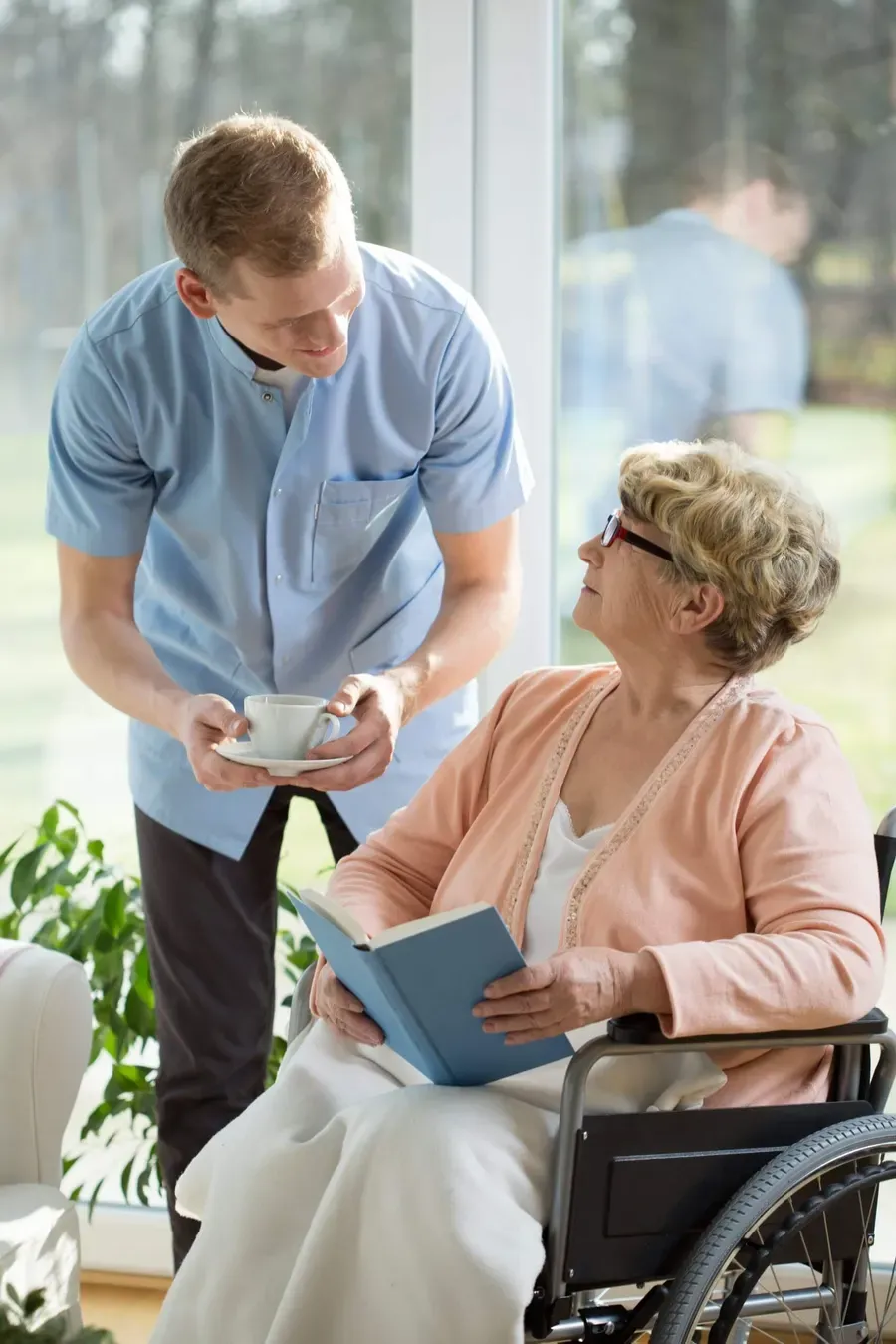 A support worker bringing a cup of tea to a smiling older woman at home
